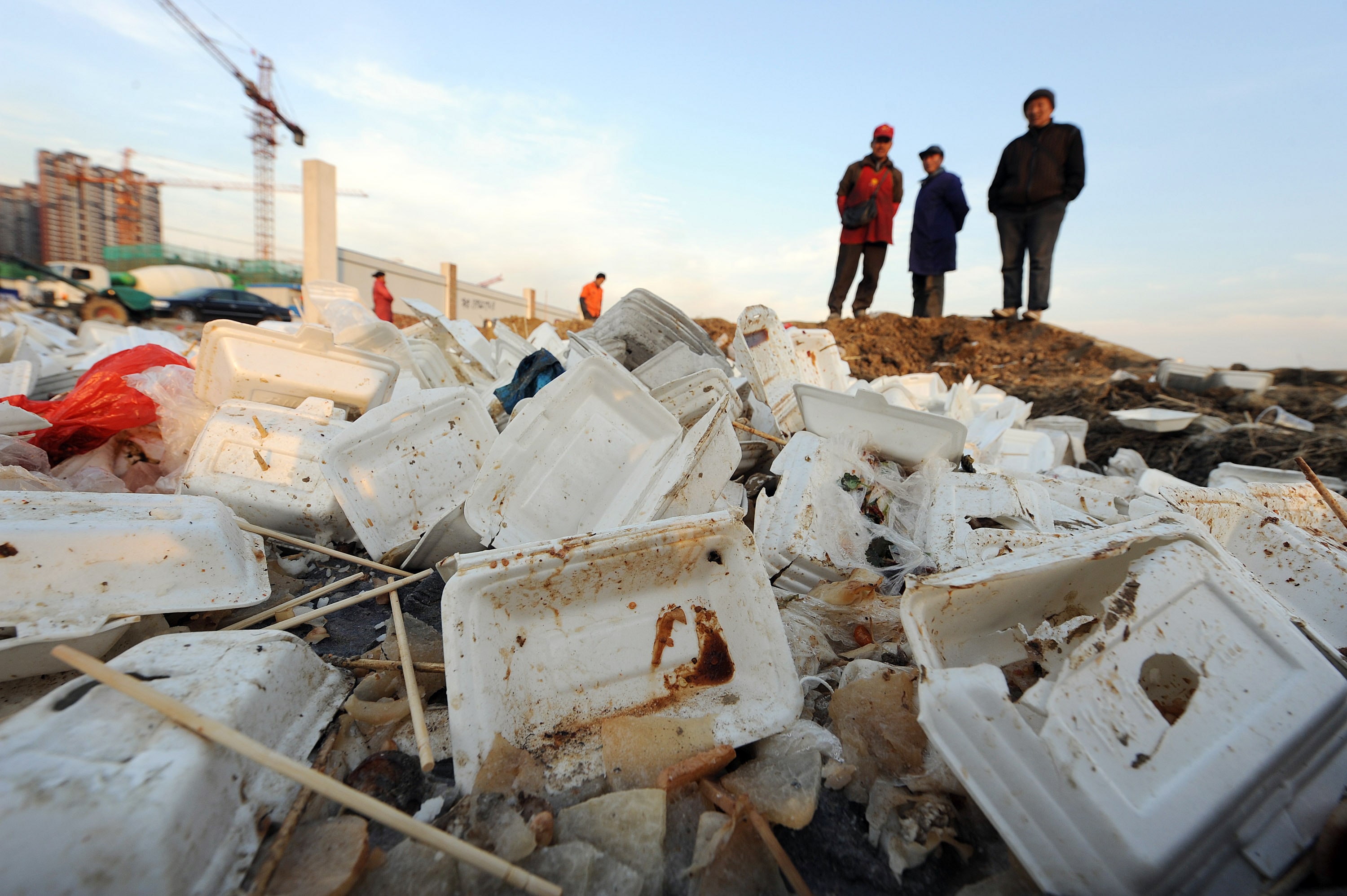 Workers stand over piles of used white p